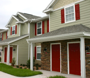 Row of townhomes with neutral siding and bold red front doors, demonstrating popular Canadian exterior paint colour choices